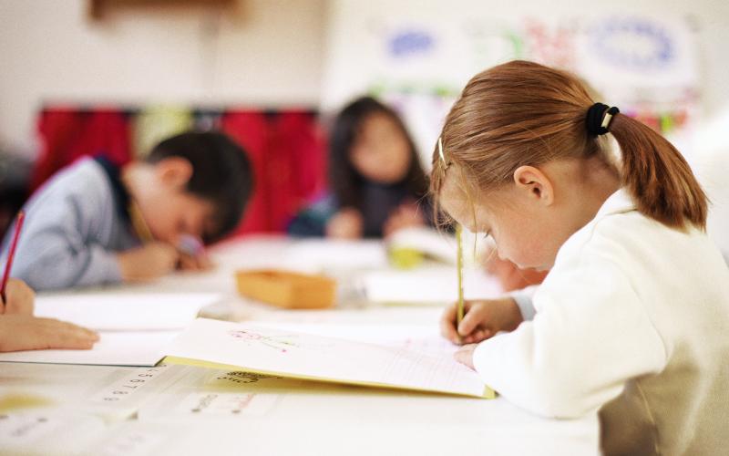 to piger og en dreng der laver opgaver i et lyst klasseværelse